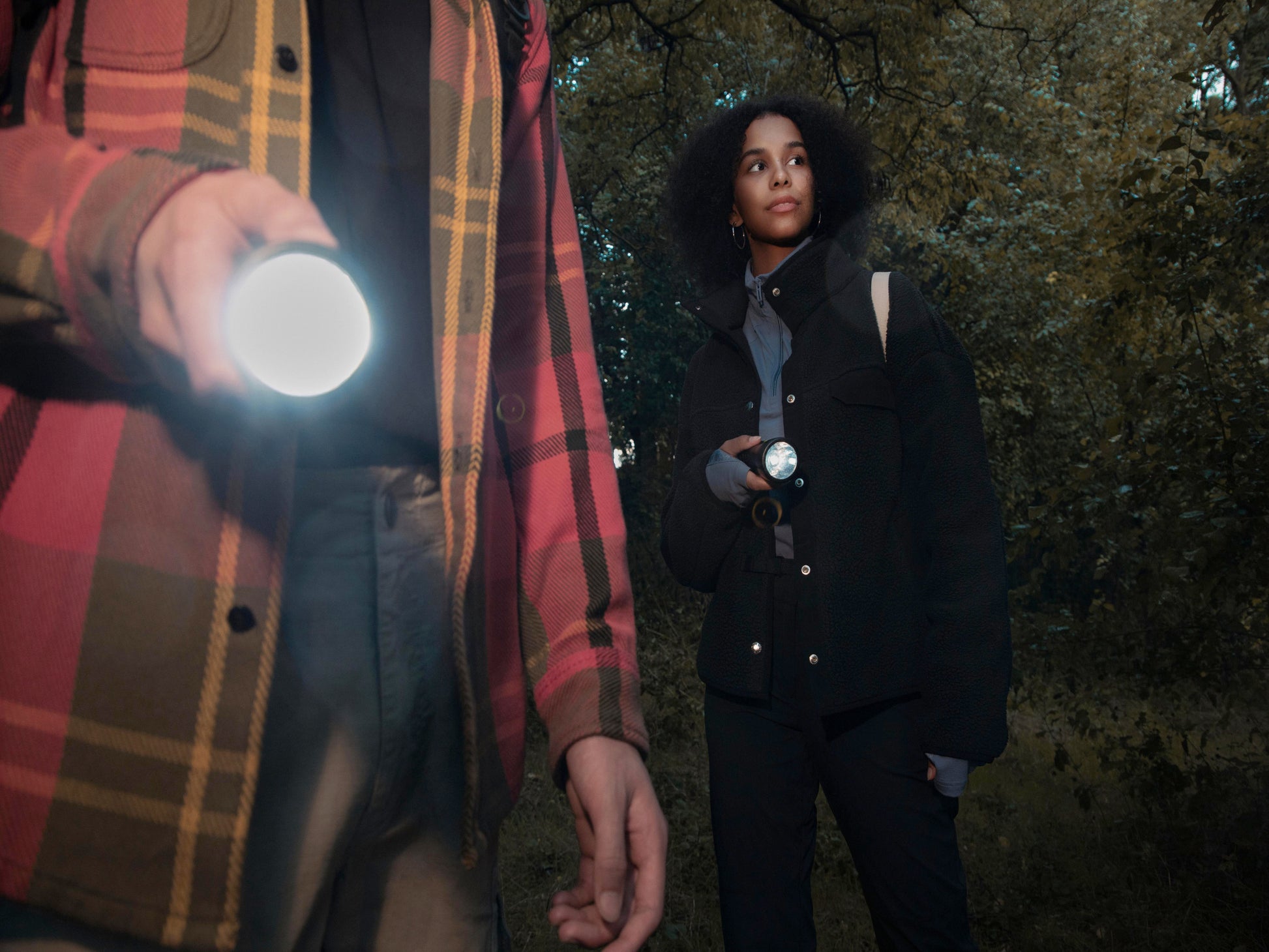 Abenteuer im Wald: Paar erlebt magische Momente mit WaterLamp-Taschenlampen. Mann im karierten Hemd hält leuchtende Taschenlampe, während die Frau ihre Lampe gen Wald leuchtet. Entdecke die Beleuchtung der Zukunft im WaterLamp Shop!